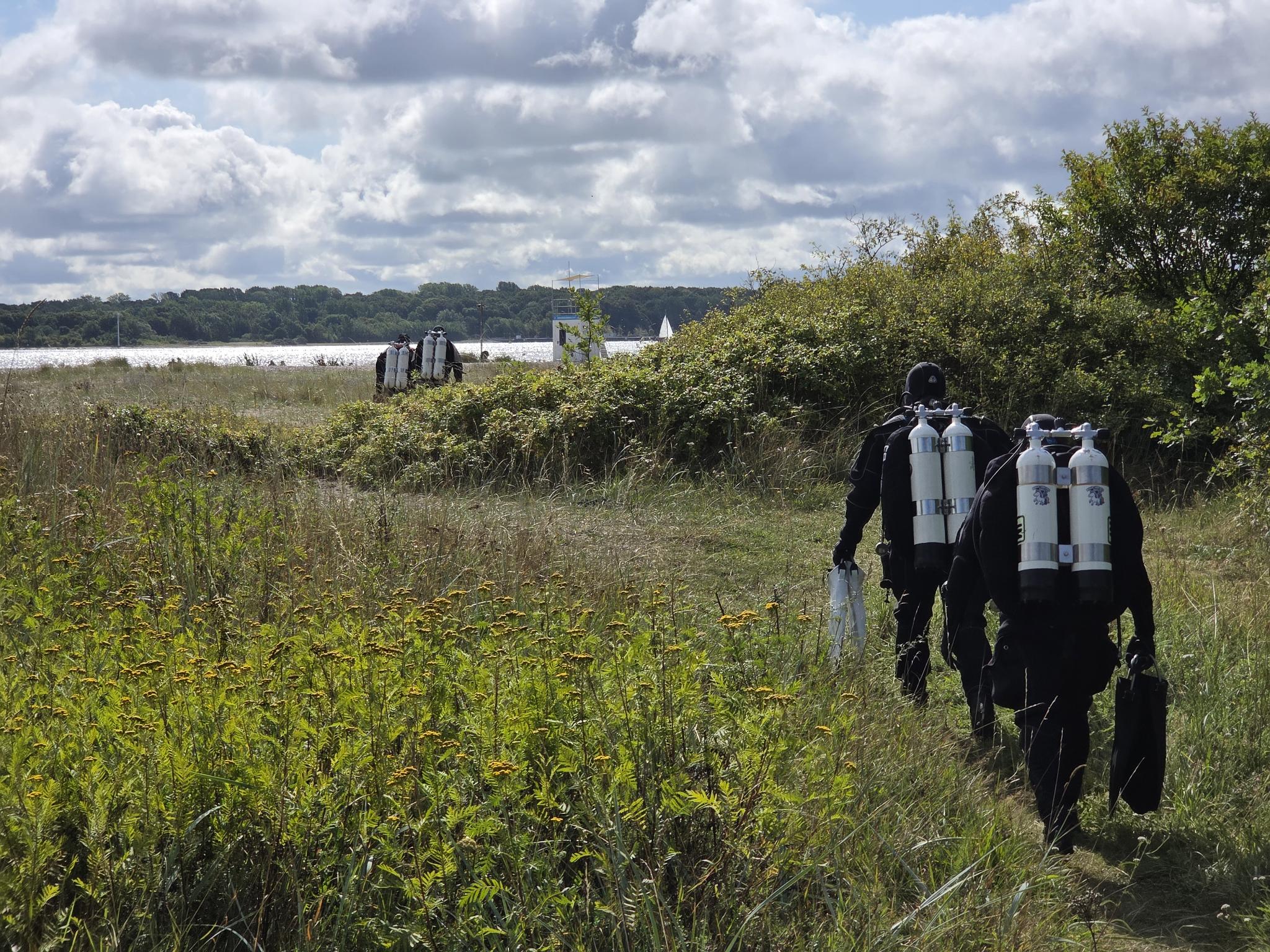 Taucher die durch die  Düne zum Tauchplatz laufen